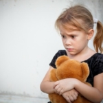 sad little girl on background the wall with toy
